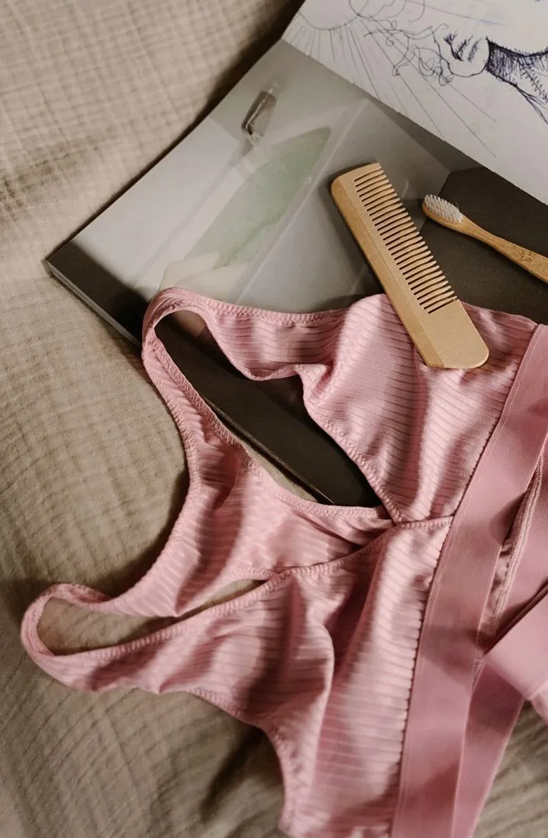 Pink ribbed top laid flat next to a wooden comb